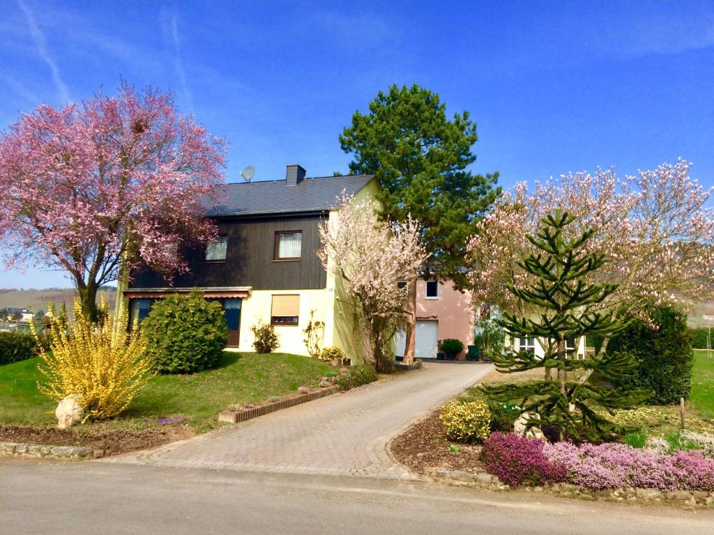 a house with flowering trees and a driveway at GästeHaus Auler Hof in Kröv