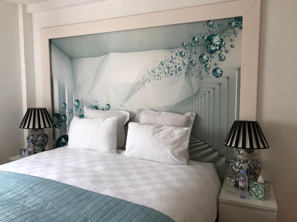 ロンドンにあるAffordable Lux and Cozy 1 bed flat in Chelseaのベッドルーム1室(青と白のベッド、ランプ2つ付)