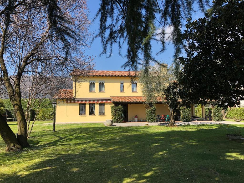 une grande maison jaune avec des arbres devant elle dans l'établissement Le Tre Querce B&B, à Romano D'Ezzelino