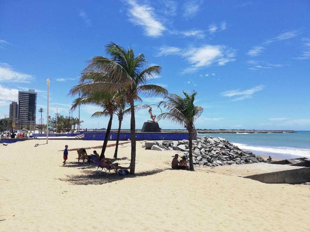 un grupo de personas sentadas en una playa con palmeras en Porto de Iracema Residence en Fortaleza