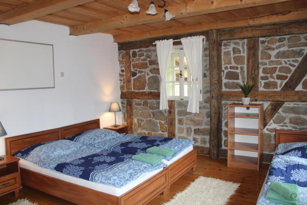 1 dormitorio con cama y pared de piedra en Penzion Modrý Svět, en Loket