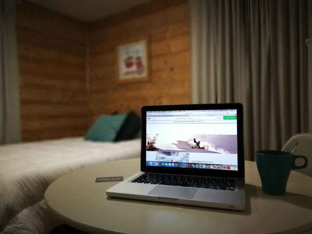 un ordenador portátil sentado en una mesa en una habitación de hotel en L'Appart'hôtel du Pic, en Taninges