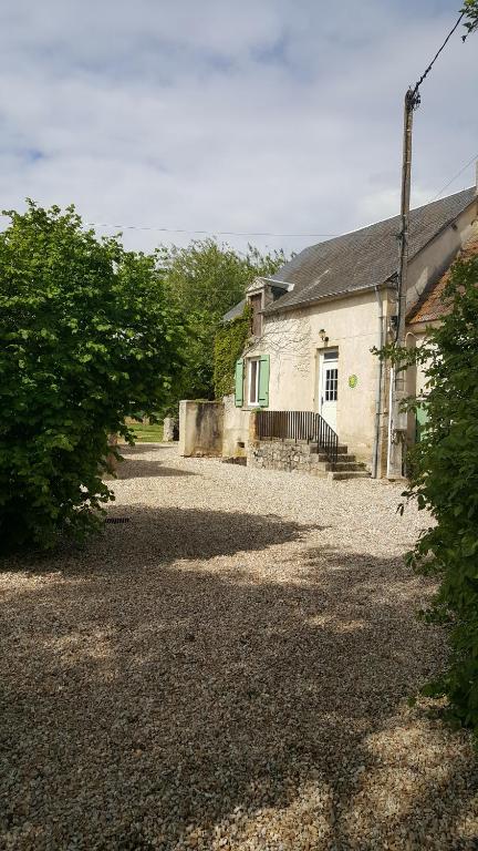 a house with a gravel driveway next to a building at Gîte Le Campagnard in Saint-Germain-des-Bois