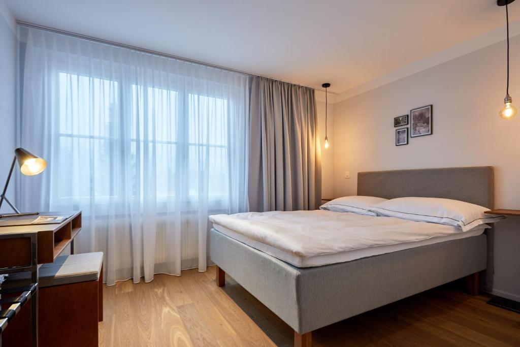 ein Schlafzimmer mit einem Bett und einem großen Fenster in der Unterkunft Italian Lifestyle Hotel & Osteria Chartreuse in Thun