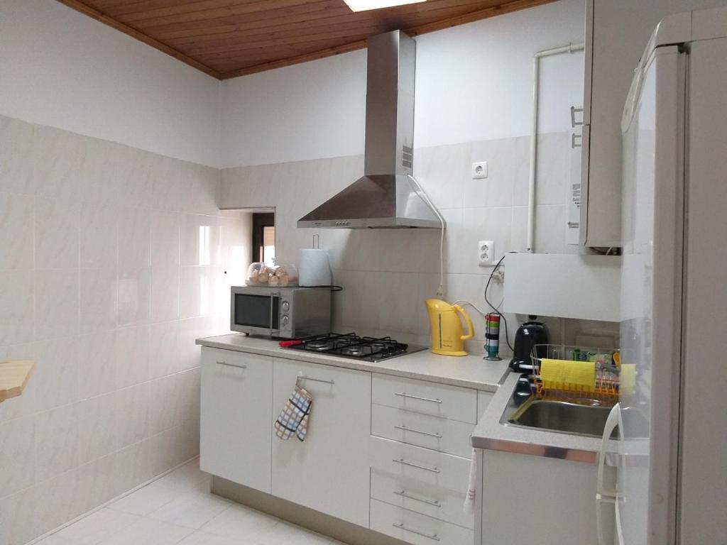 een witte keuken met een wastafel en een fornuis bij Farol de vida 2 in Coimbra