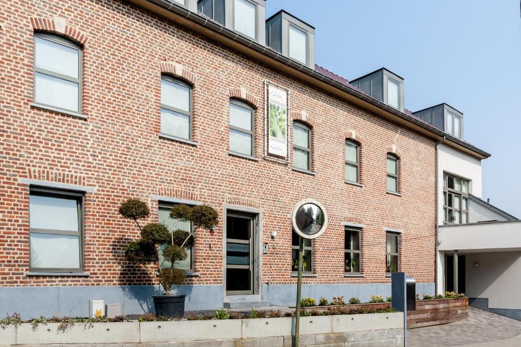 un bâtiment en briques rouges avec des plantes devant lui dans l'établissement Gastenhof Ter Lombeek, à Lombeek-Notre-Dame