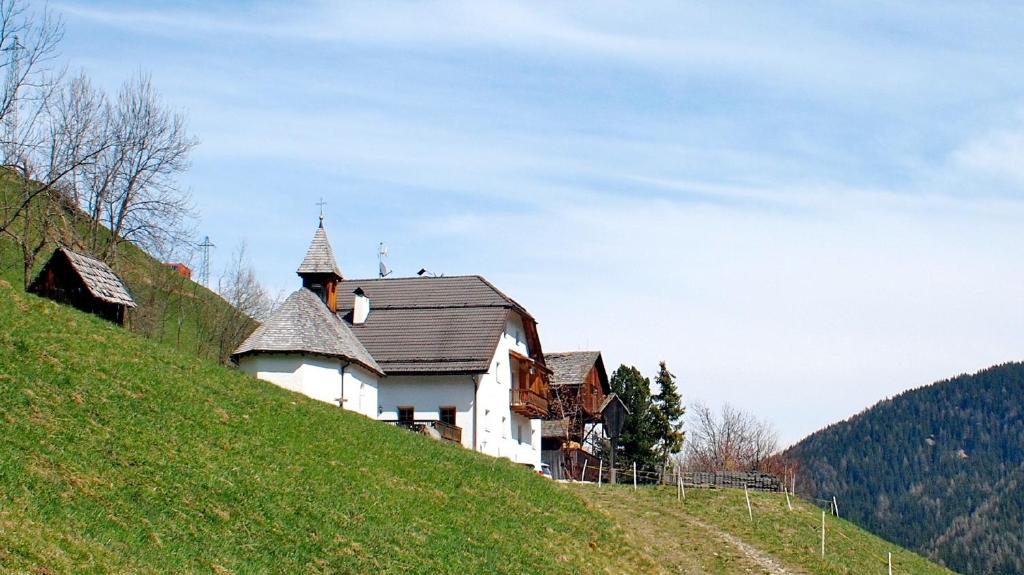 a house on a hill with a church on it at Berggasthof Trattes in Valdaora