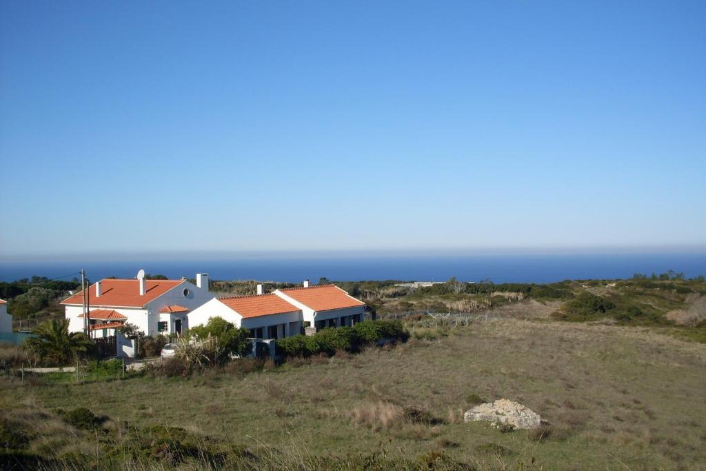 a house on a hill with the ocean in the background at Cozy Country House near Beaches in Azoia