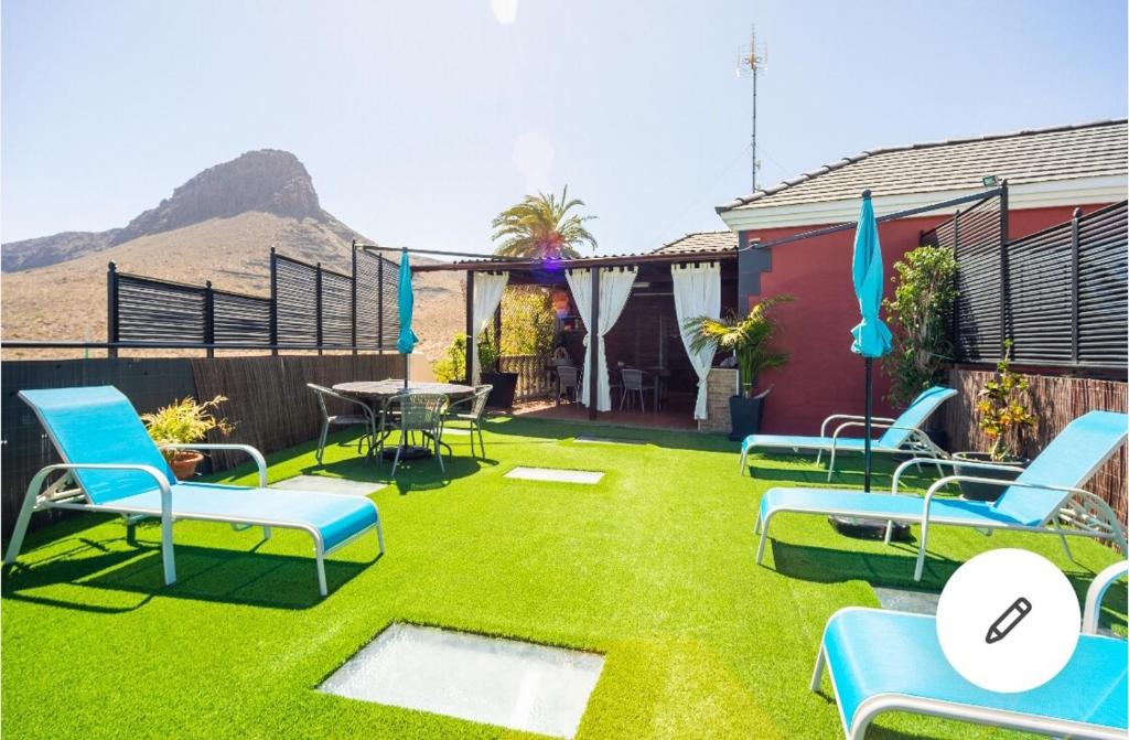 een achtertuin met stoelen, een tafel en gras bij Casa Roque Aguayro in Agüimes