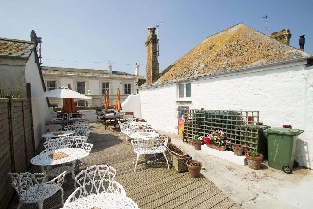 a patio with white chairs and tables and a building at Rosario in Marazion