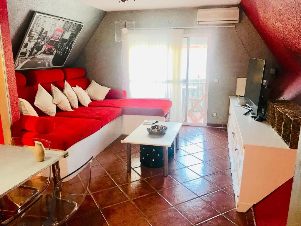 ein Wohnzimmer mit einem roten Sofa und einem Tisch in der Unterkunft Duplex La Cala in La Cala del Moral