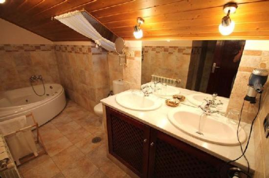 uma casa de banho com 2 lavatórios, uma banheira e um WC. em Casa Suarna em Navia de Suarna