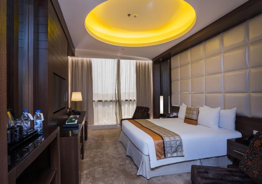 a hotel room with a bed and a yellow ceiling at Gloria Inn Riyadh in Riyadh