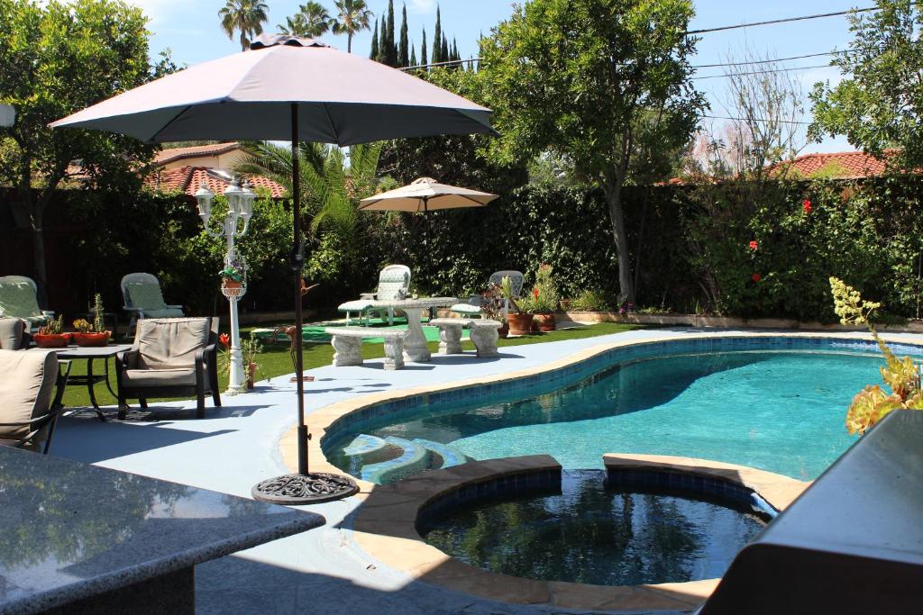 una piscina con sombrilla, mesa y sillas en Sweet Dreams B&B LA en Sherman Oaks