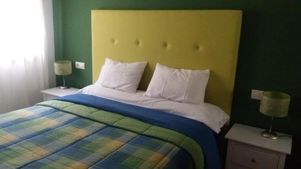 ルーゴにあるPenínsula de la pazのベッドルーム1室(黄色のヘッドボードと白い枕のベッド1台付)