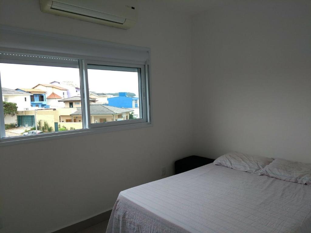 um quarto branco com uma cama e uma janela em Domus Angelis em Cachoeira Paulista