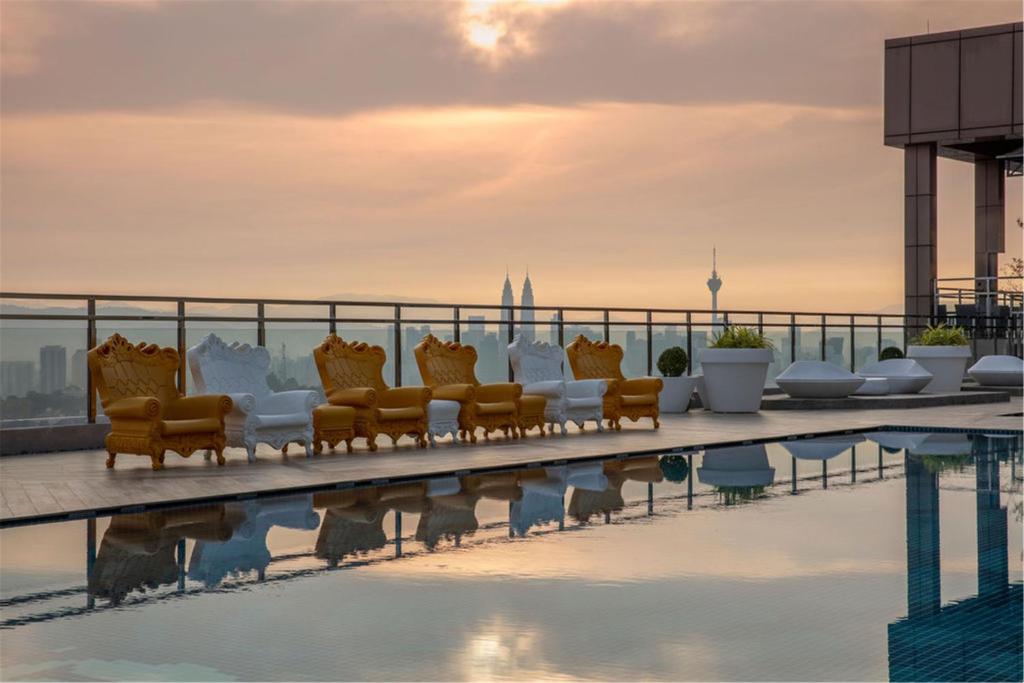 A rooftop pool deck with skyline views and decorative lounge seating.