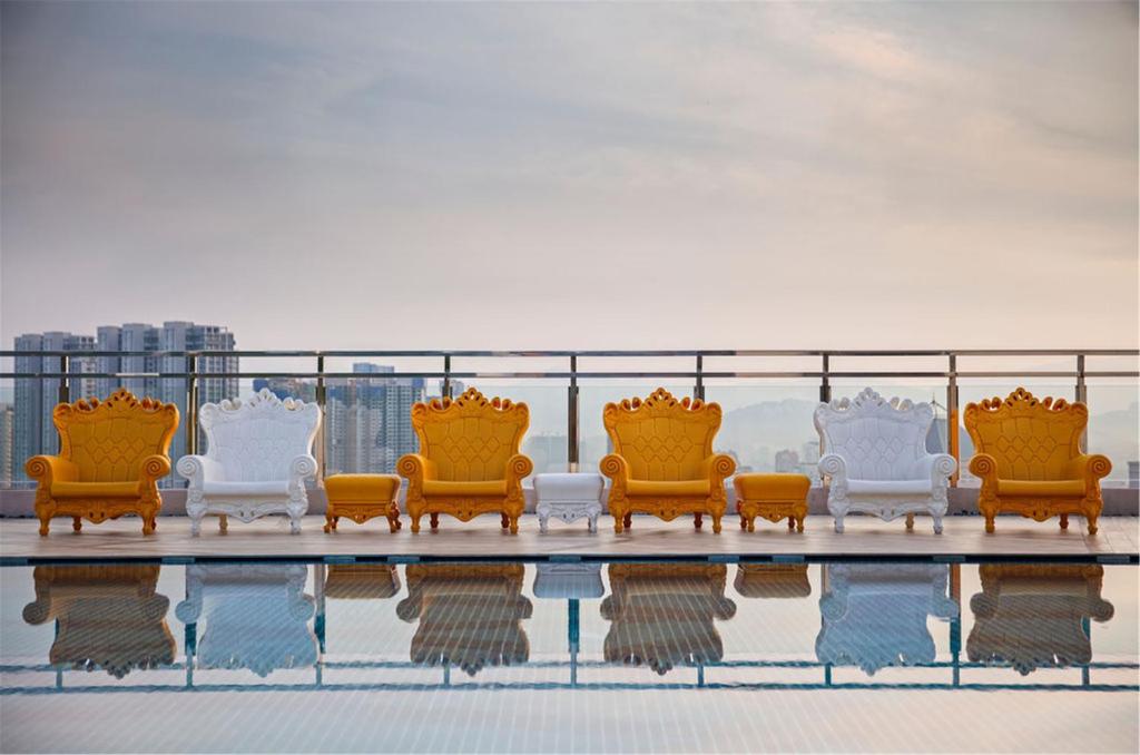 A rooftop pool deck lined with ornate statement chairs.