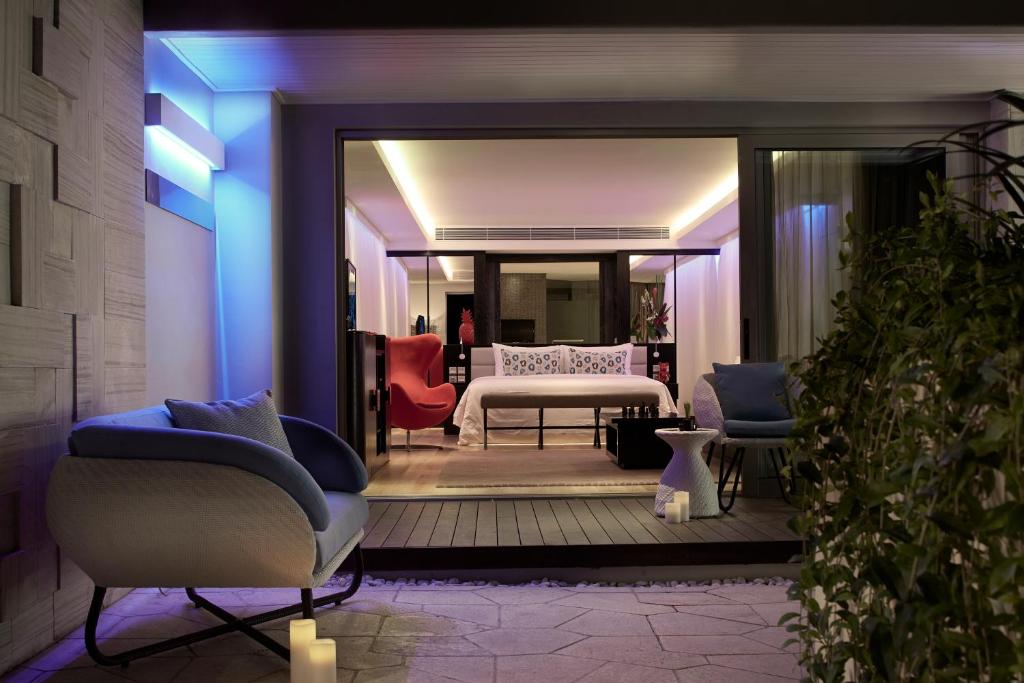 a room with a bedroom with a bed and chairs at Double - Six, Luxury Hotel - Seminyak in Seminyak