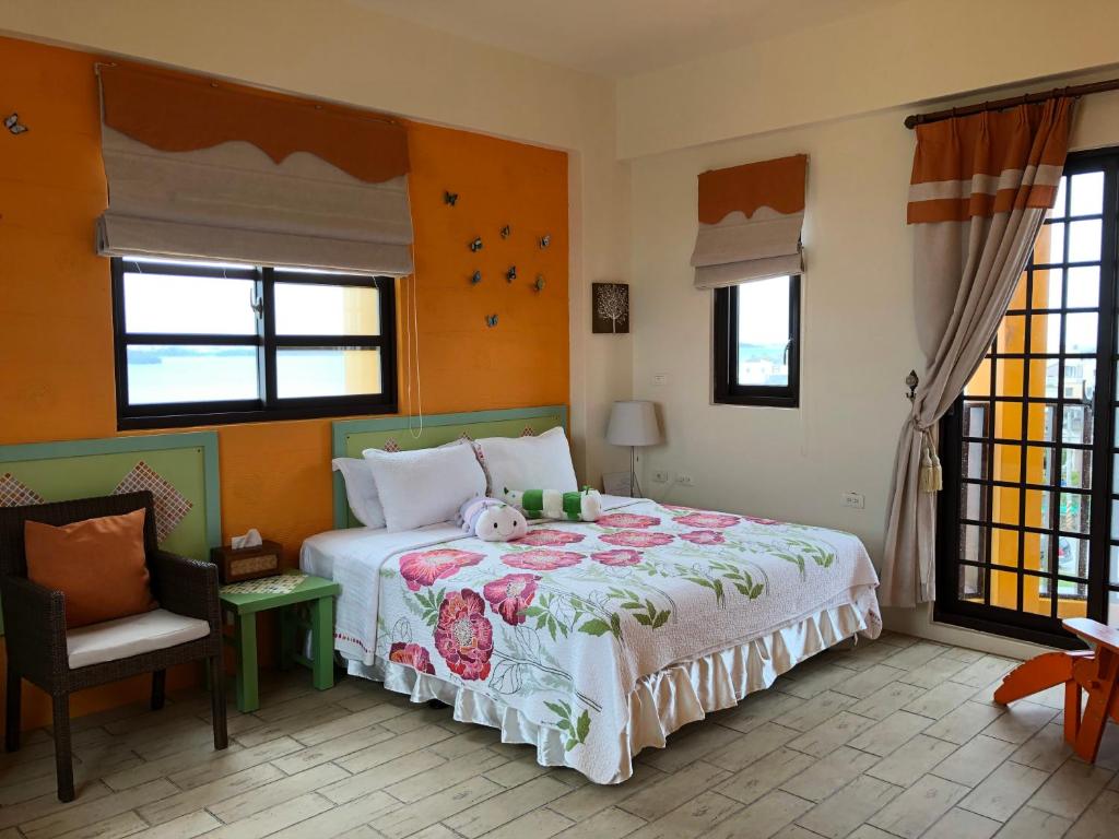 a bedroom with a bed and a chair and windows at Remember Sea View B&B in Huxi