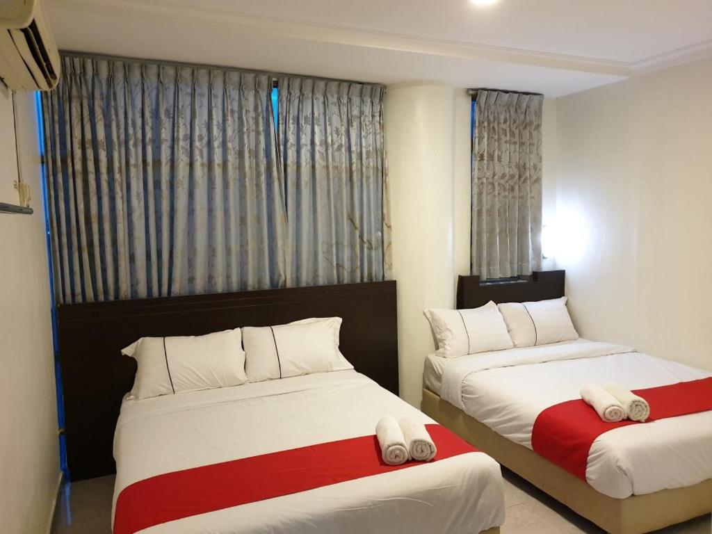 a bedroom with two beds with white and red sheets at Fully Hotel Desa Tebrau in Johor Bahru