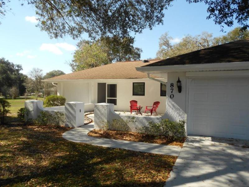 a white house with a garage and two red chairs at Foxrun Retreat - 3BR Inverness Poolhome in Inverness