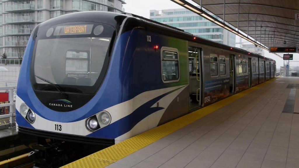 a blue and white train at a train station at Bed Plus YVR in Richmond