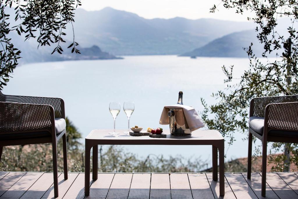 a table with two chairs and a table with wine glasses at Hotel Miranda in Riva di Solto