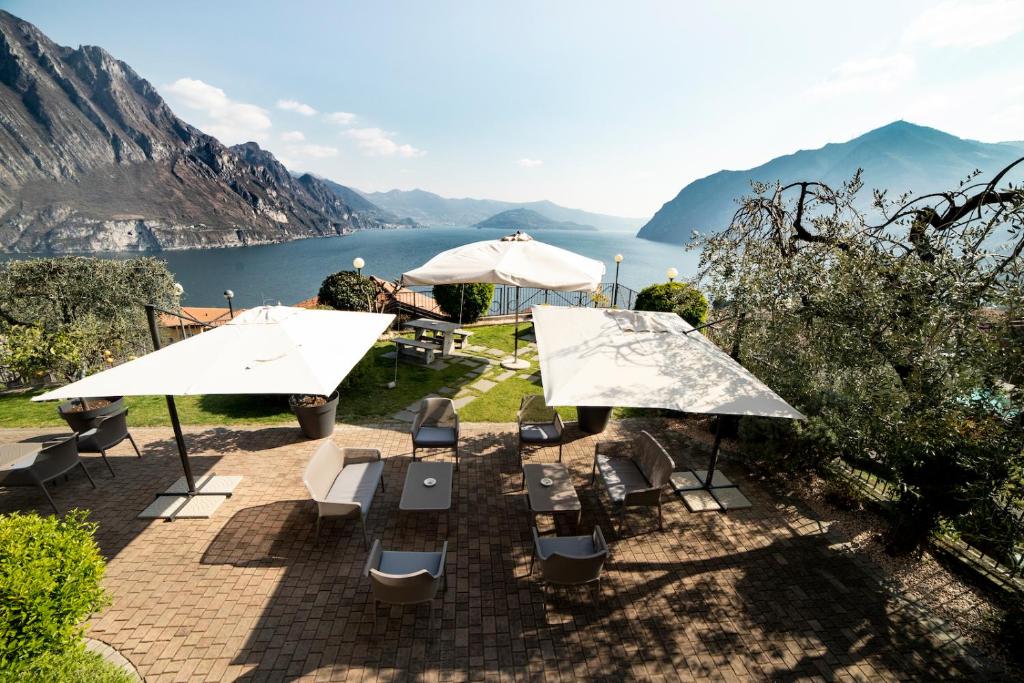 a patio with tables and umbrellas and a lake at Hotel Miranda in Riva di Solto