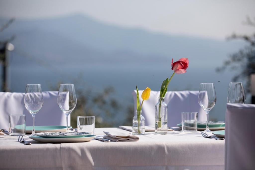 a table with glasses and a rose in a vase at Hotel Miranda in Riva di Solto