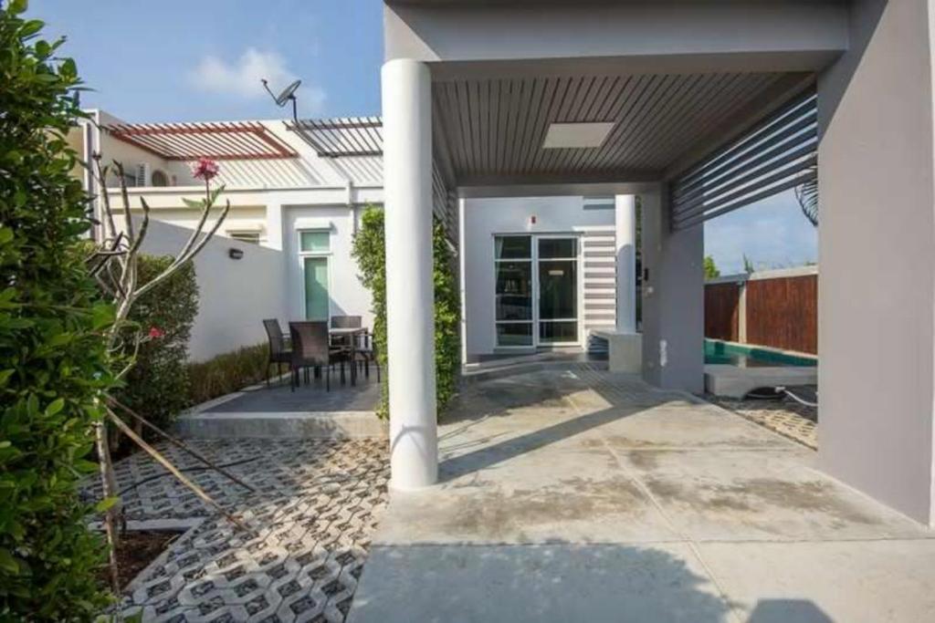 a white house with a patio with a pool at Paknampran 2 Bedrooms Pool Villa in Pran Buri