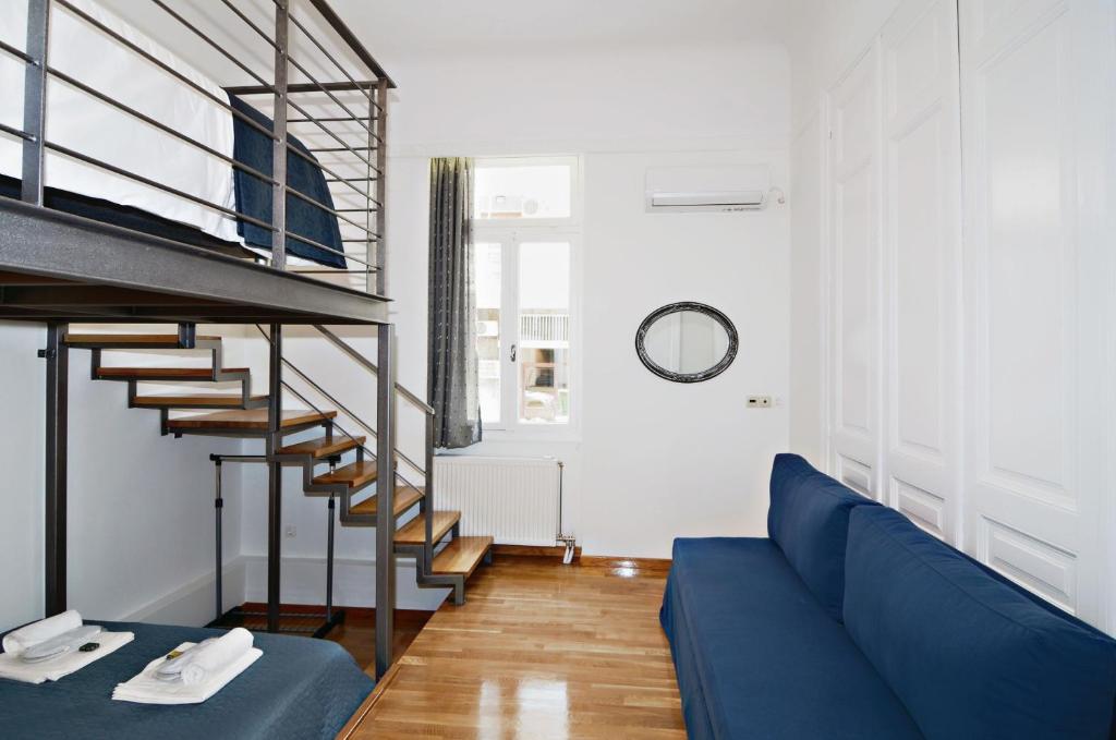 a living room with a blue couch and a spiral staircase at Neoclassical House with Unique Athenian Yard (nearby metro station) in Athens