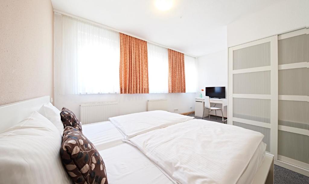 a bedroom with a white bed and a desk at Altstadthotel Fürth in Fürth