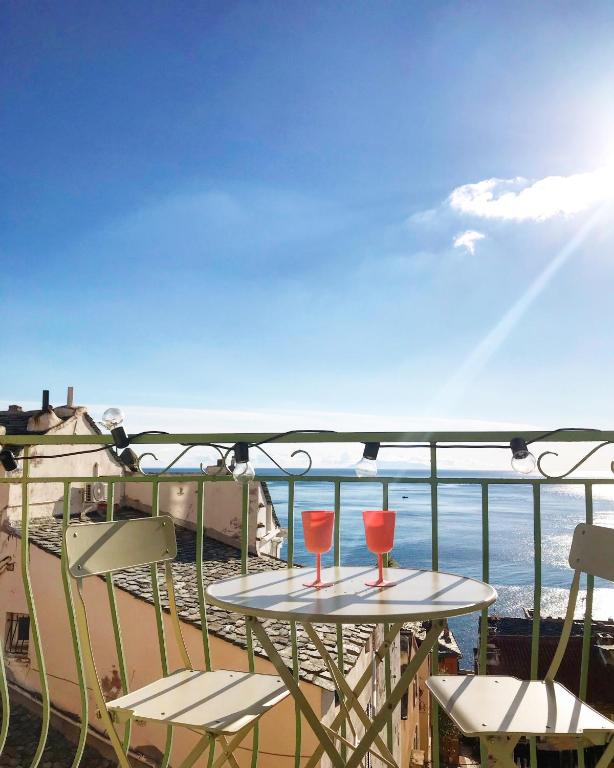 une table et des chaises sur un balcon avec vue sur l'océan dans l'établissement CASADELLA - Casa Vista Mare Citadelle, à Bastia