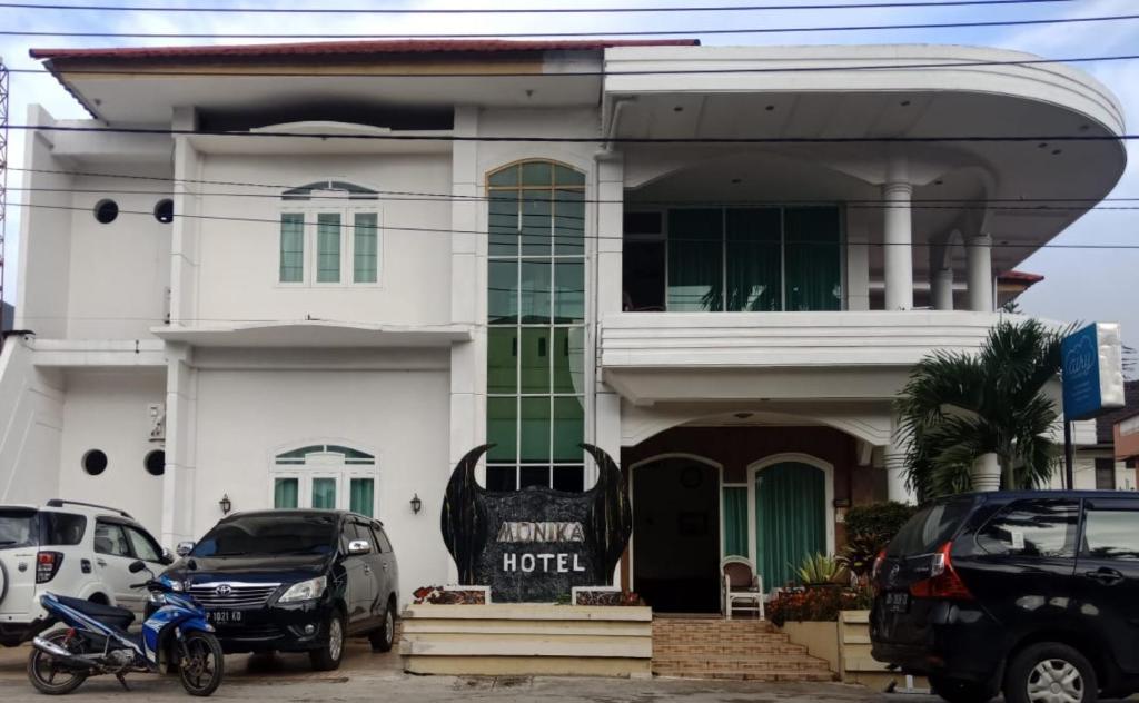 a white house with cars parked in front of it at Hotel Monika in Rantepao