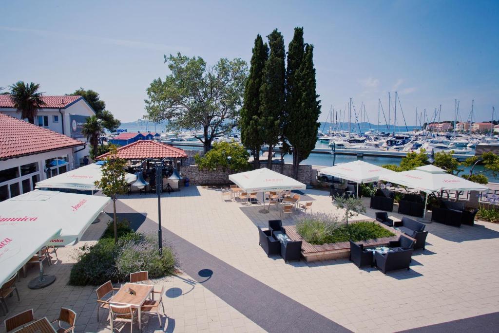 un patio al aire libre con mesas y sombrillas y un puerto deportivo en HI Hostel Zadar en Zadar