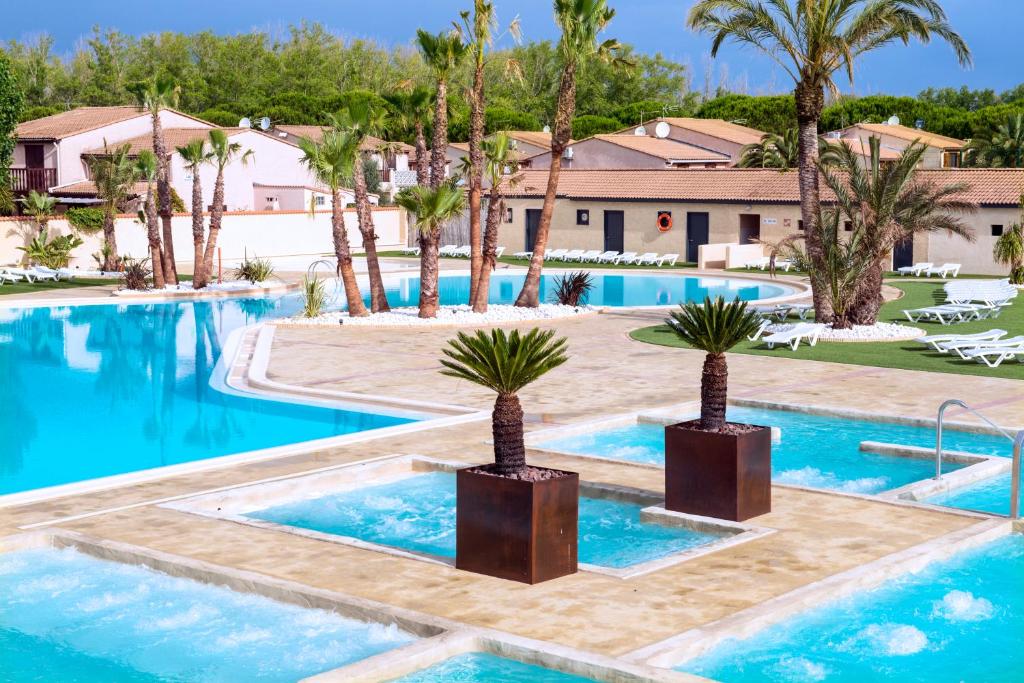 a swimming pool with palm trees and a resort at Les Tamaris et Les Portes du Soleil in Portiragnes
