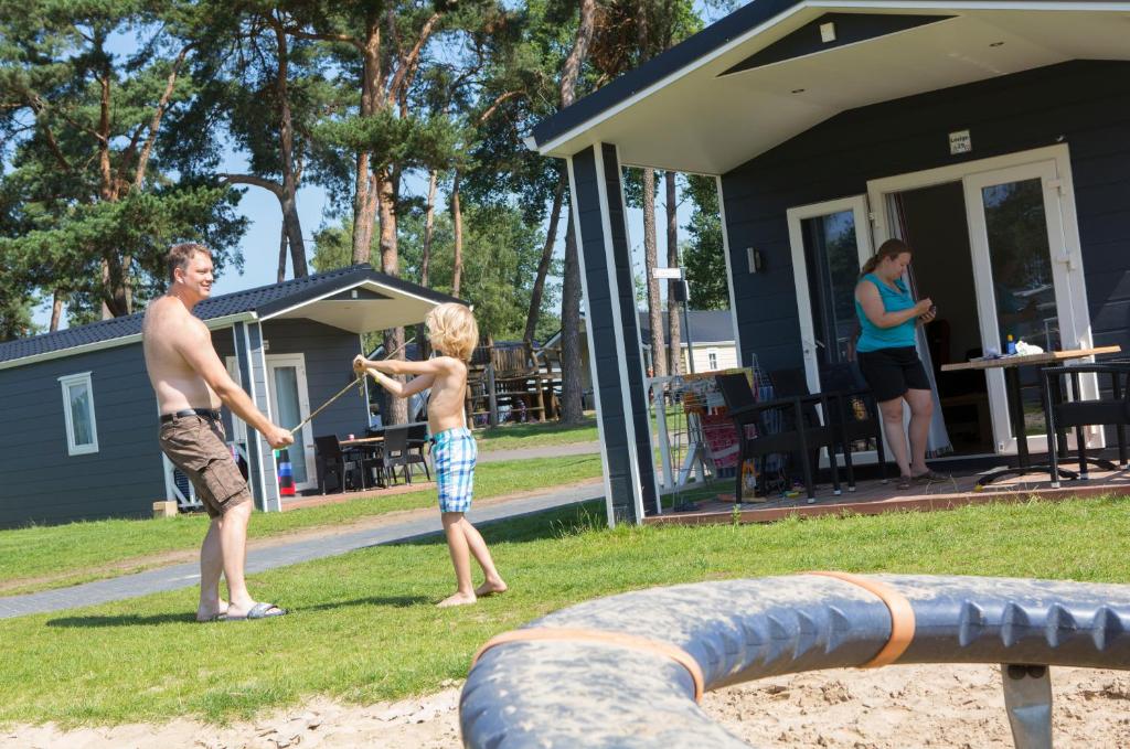 un homme et un jeune garçon jouant avec un ballon dans l'établissement Lodge 4 personen camping de Molenhof, à Reutum