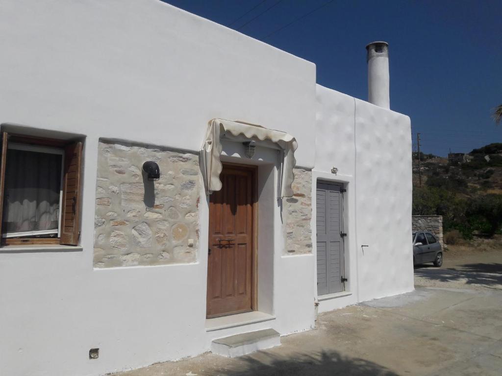 biały budynek z drewnianymi drzwiami i oknem w obiekcie elaiolithos w mieście Kóstos