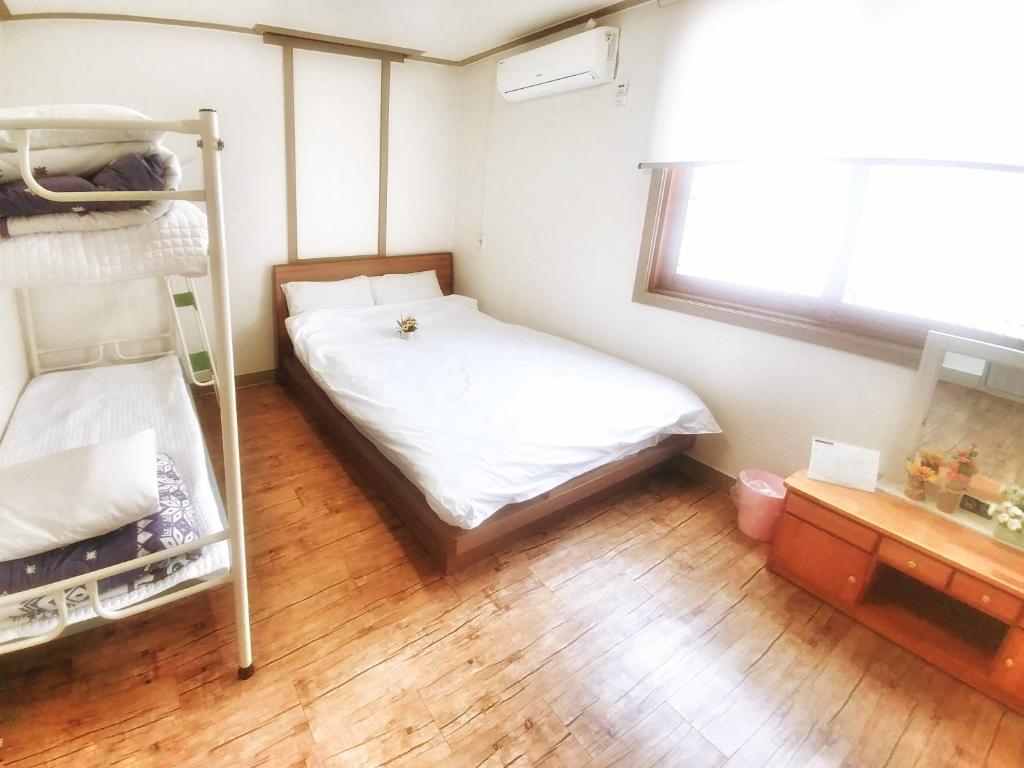 1 dormitorio con litera y suelo de madera en Jeju Masil Guesthouse en Jeju