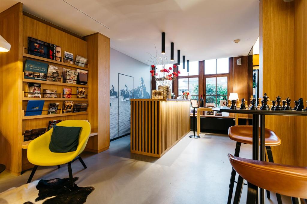 a living room with a yellow chair and a table at Boutique Hotel 'Hof ter Duinen' in Oostduinkerke