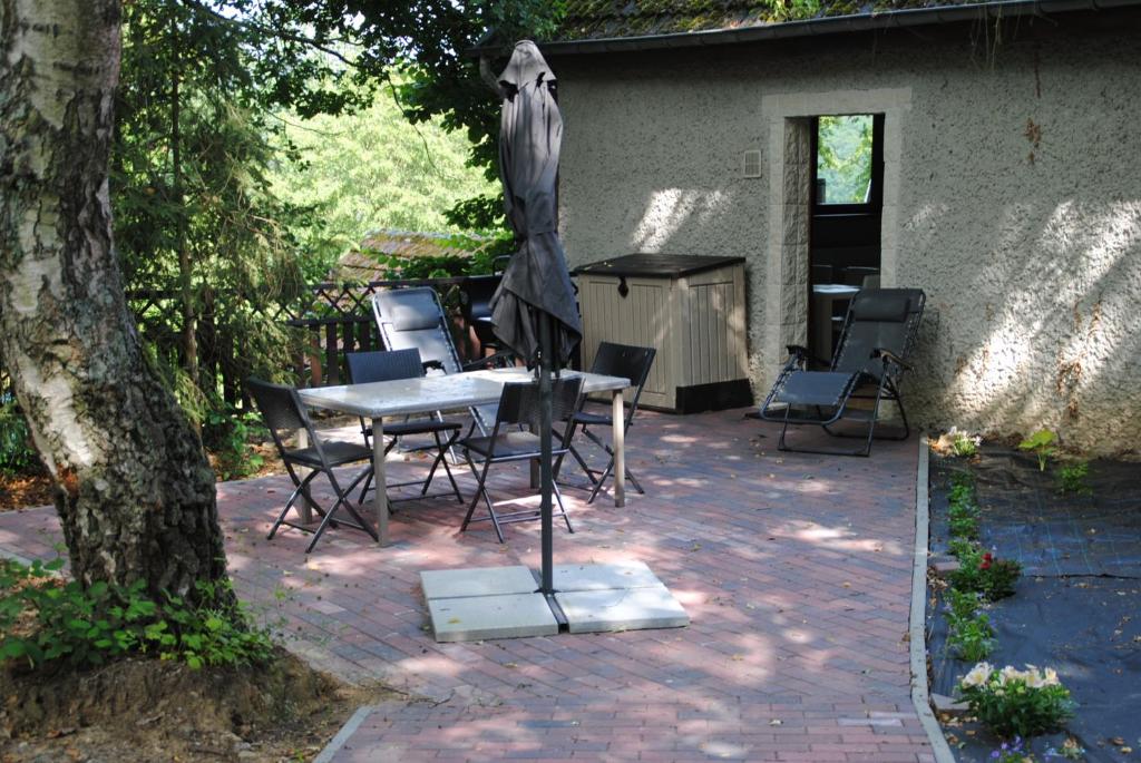 een patio met een tafel en stoelen en een parasol bij Gite chez Phil in Durbuy