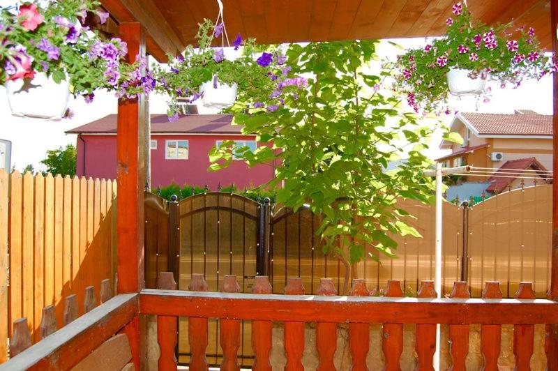 a wooden fence with a tree and purple flowers at Casa cu Castan in Eforie Nord