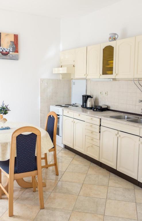 a kitchen with white cabinets and a table and chairs at Apartment Sv. Marak in Risika