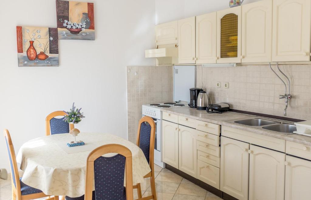 a kitchen with white cabinets and a table and a sink at Apartment Sv. Marak in Risika