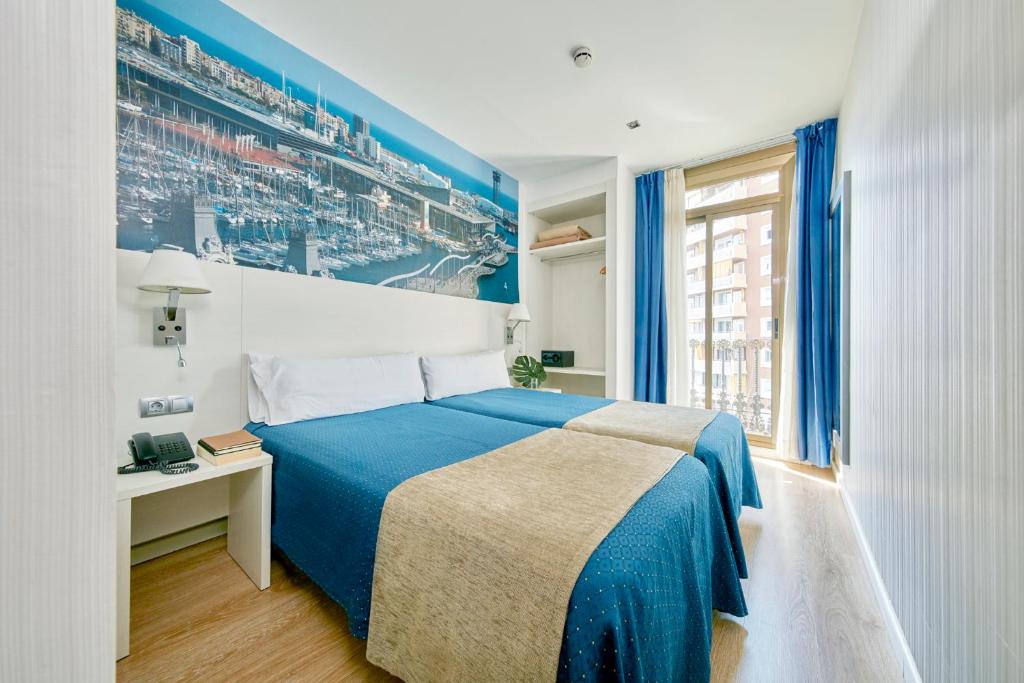 a bedroom with a blue and white bed and a window at Hotel Transit in Barcelona