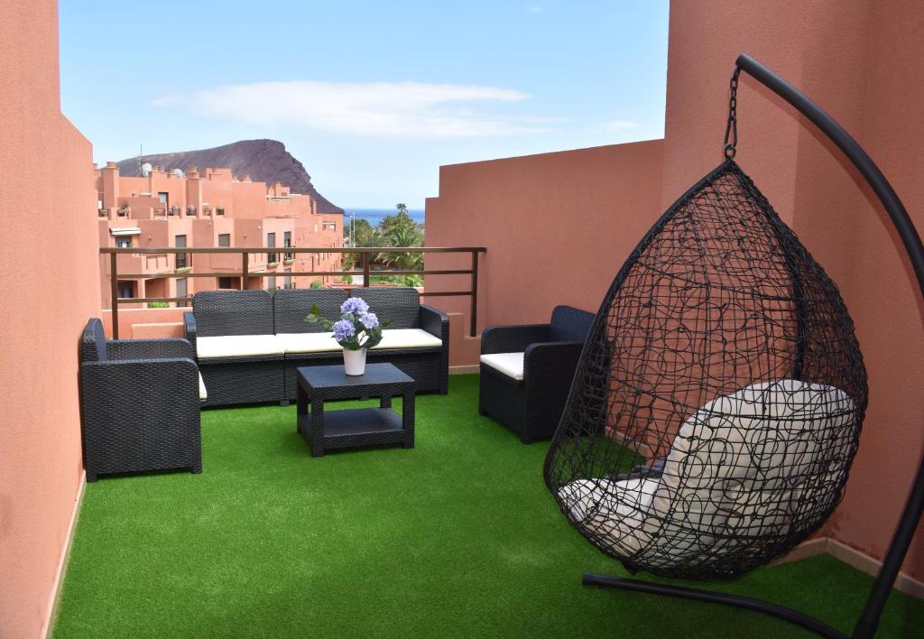 a patio with a swing on a balcony with green grass at VILLA MOLEIRO- LA TEJITA in La Tejita