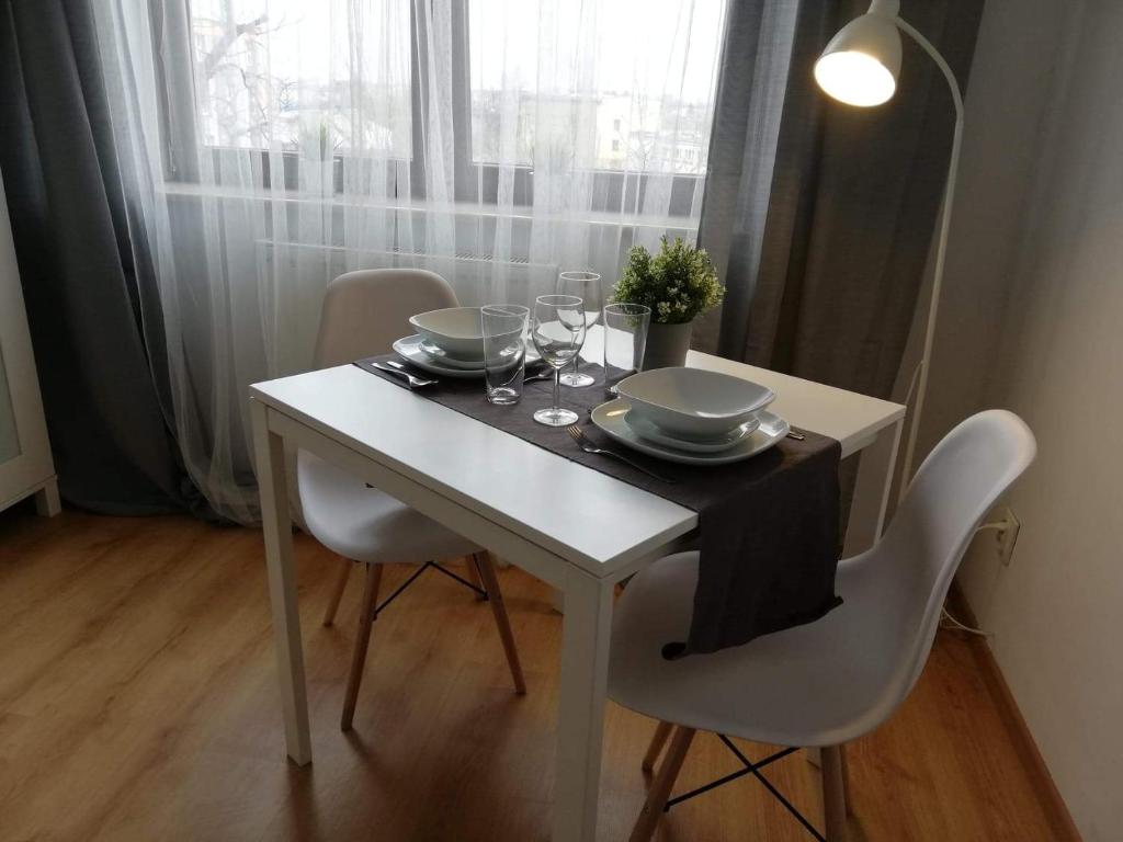 チェンストホヴァにあるPokoje przy Rondzieの白いテーブル(椅子、皿、ワイングラス付)