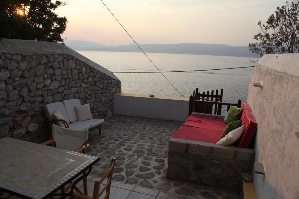 a patio with a table and chairs and the water at Alkioni stone house in Hydra