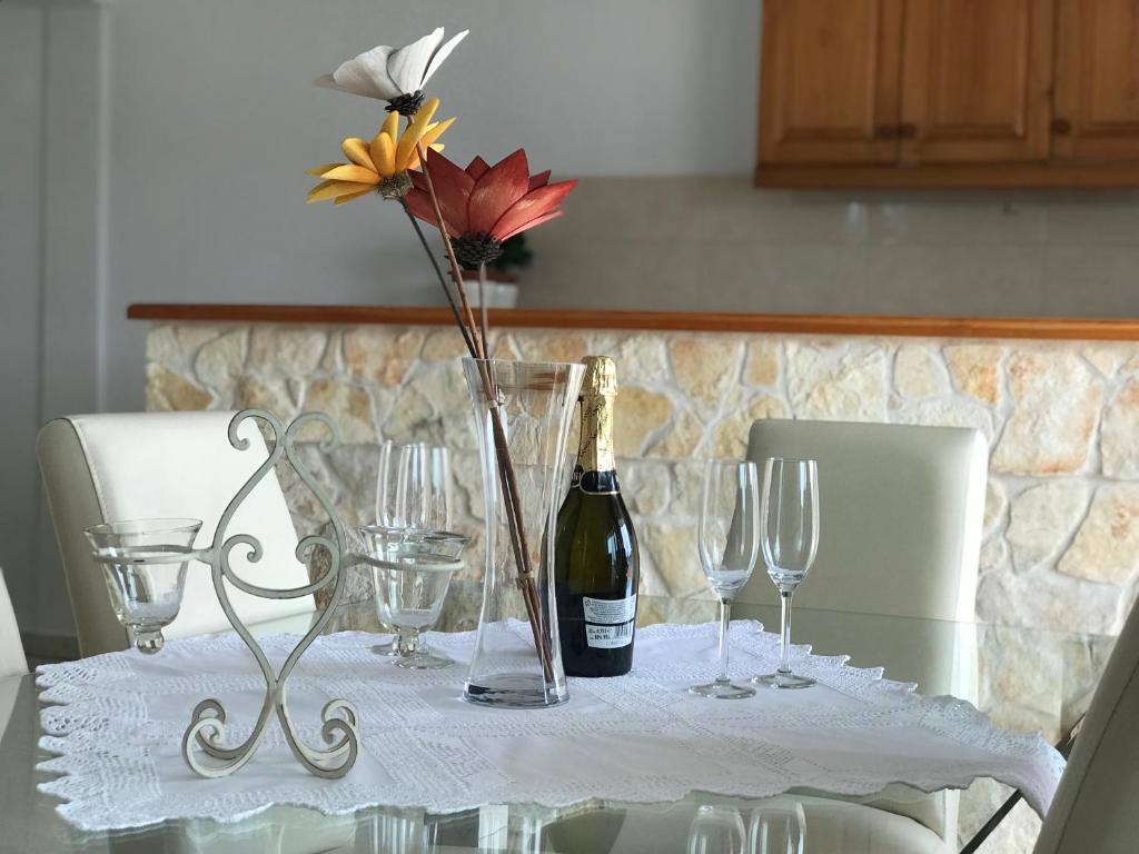 a table with a bottle of wine and glasses on it at Ivančica Apartments in Tisno